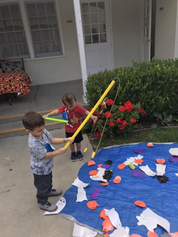 Two children playing a fishing game with cutouts on a blue tarp