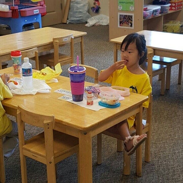 Child eating at a small table in a classroom