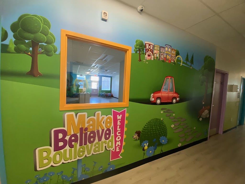 Wall mural with "Make Believe Boulevard" text and cartoon landscape