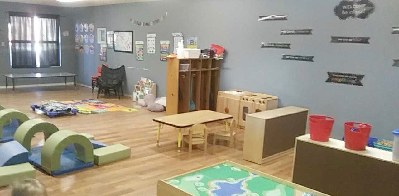 Playroom with soft play equipment, small tables, and storage units