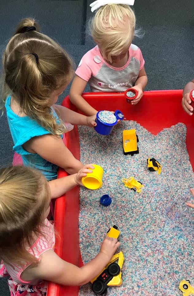 Children playing with toys in a sensory bin