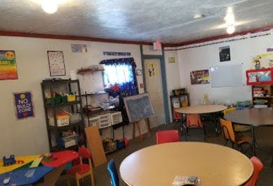 Classroom with round tables and chairs, shelves, and a window