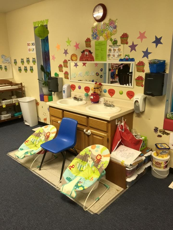 Childcare room with two sinks, a blue chair, and two infant bouncers