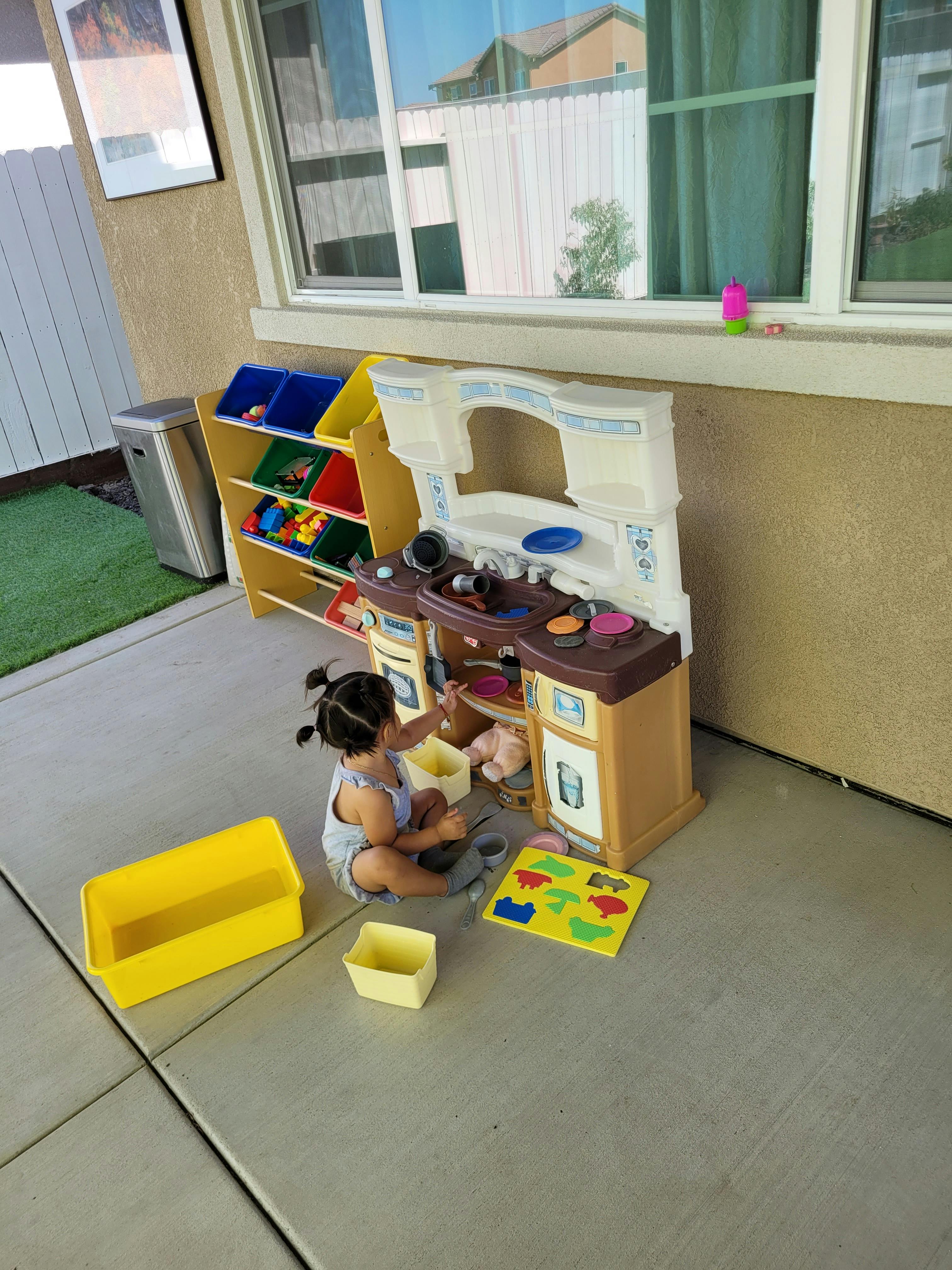 Child playing with a toy kitchen set outdoors