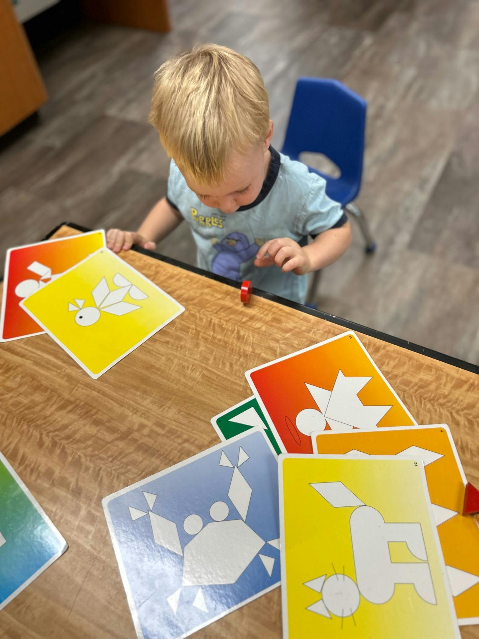 Child playing with colorful pattern cards on a table