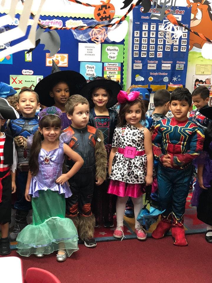 Group of children in various costumes standing in a classroom