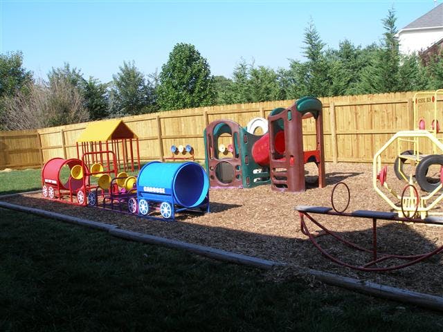 Playground with a train-shaped tunnel, climbing structure, and seesaw