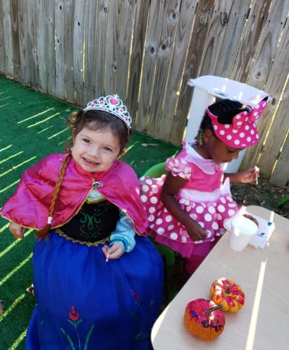 Two children in costumes sitting at a table outdoors
