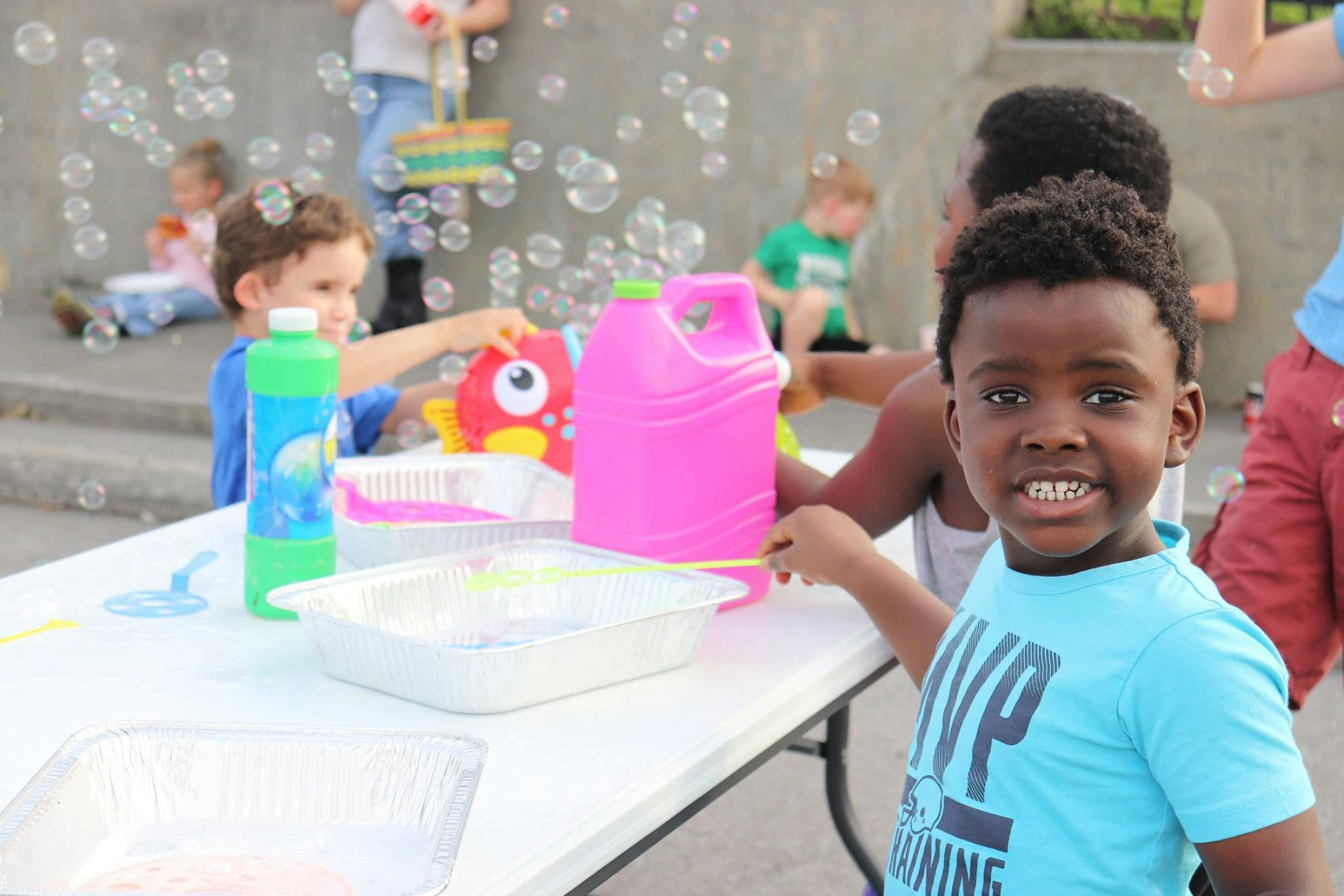 Child smiling at camera with bubbles and other children in background