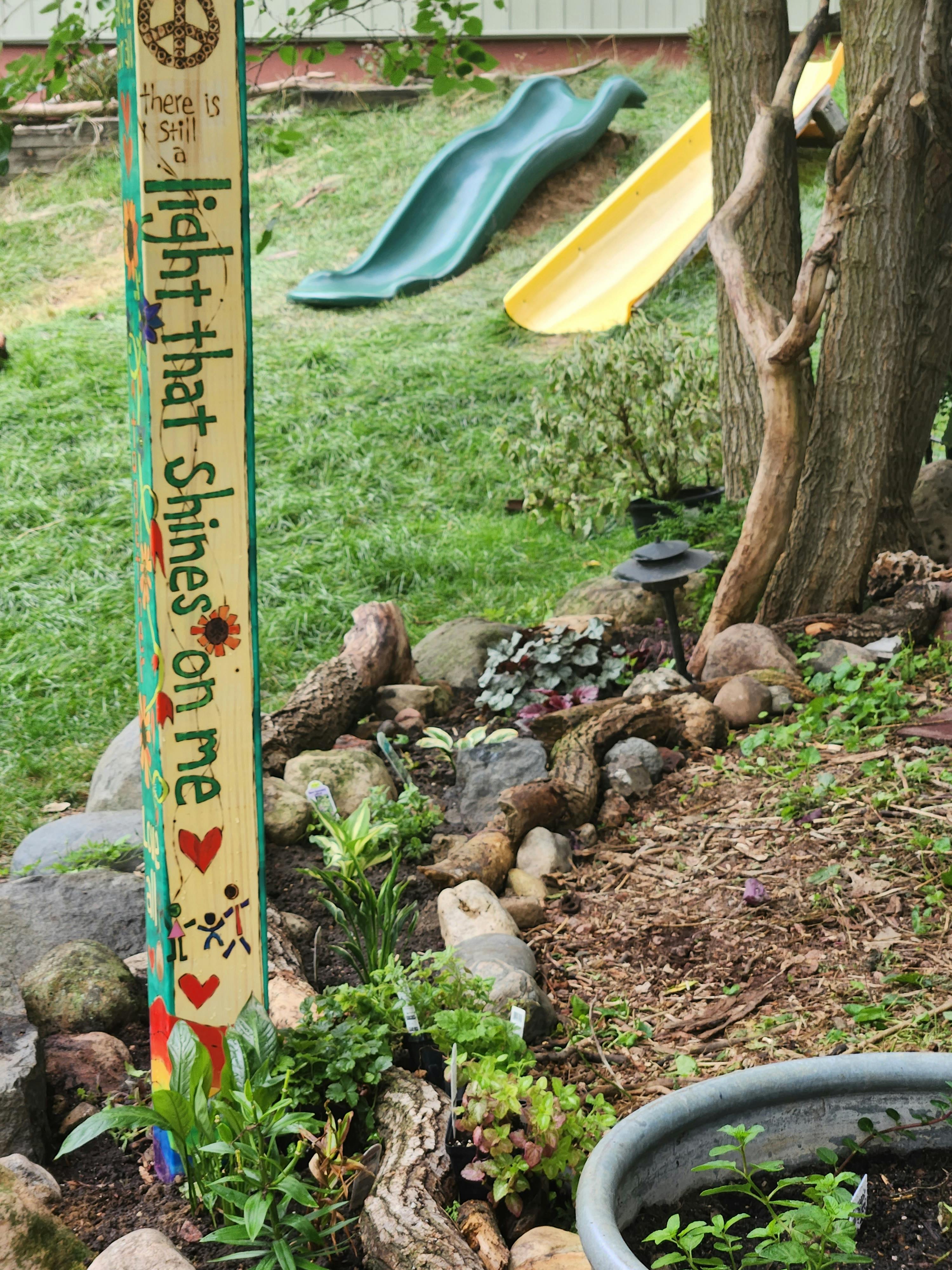 Garden with a decorative wooden post, two slides, and a tree