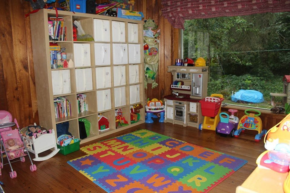 Playroom with a large storage shelf, alphabet mat, and various toys