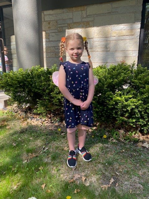 Child with pigtails wearing a butterfly print dress and fairy wings