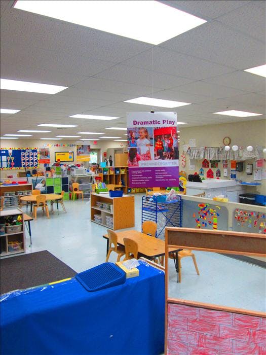 An empty kindergarten classroom with small tables and chairs