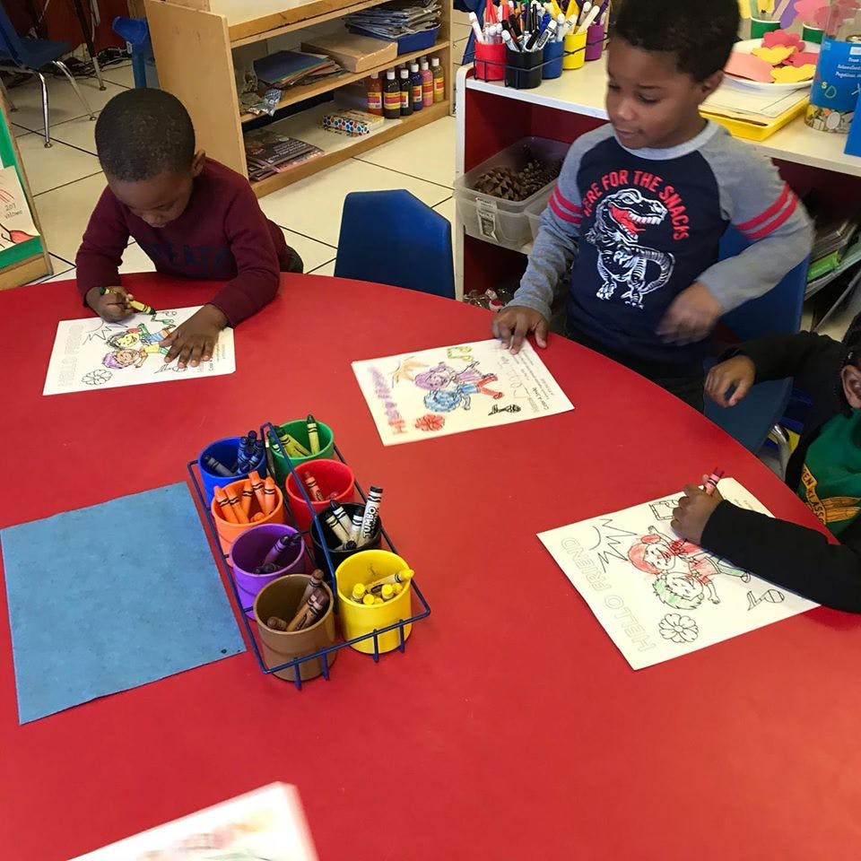 Children coloring at a red table in a classroom