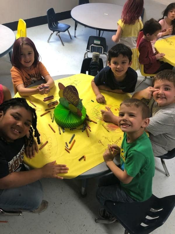 Children sitting around a table with crayons and a craft