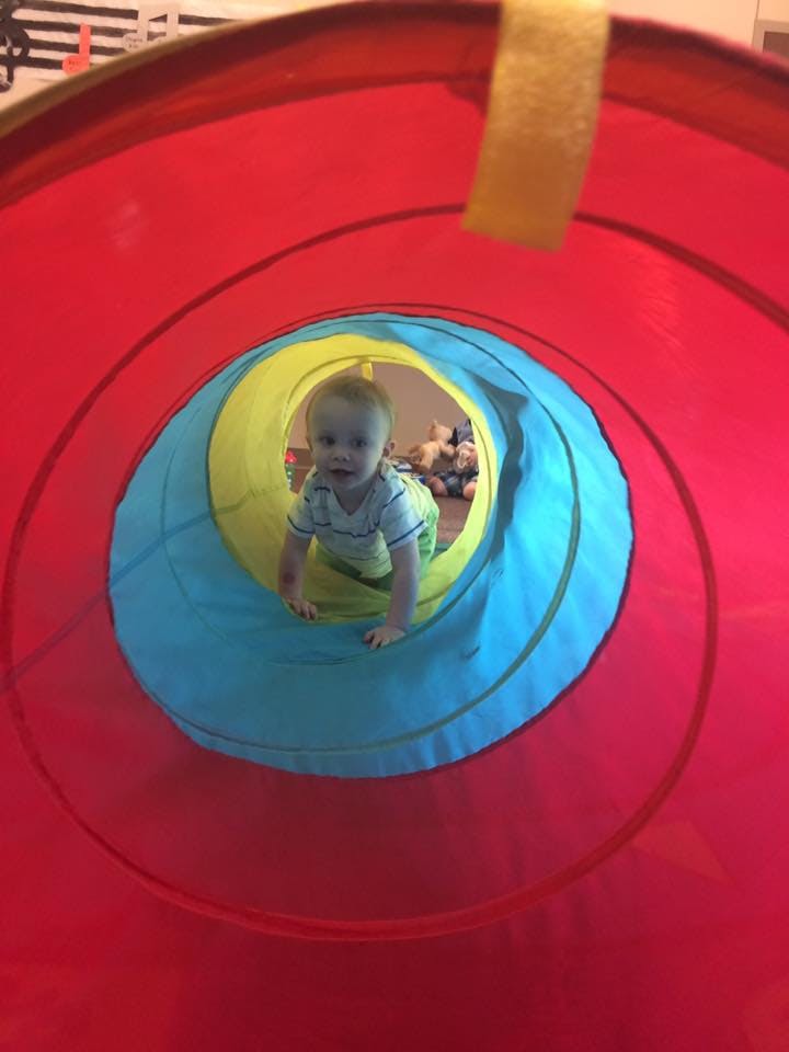 Child crawling through a colorful play tunnel