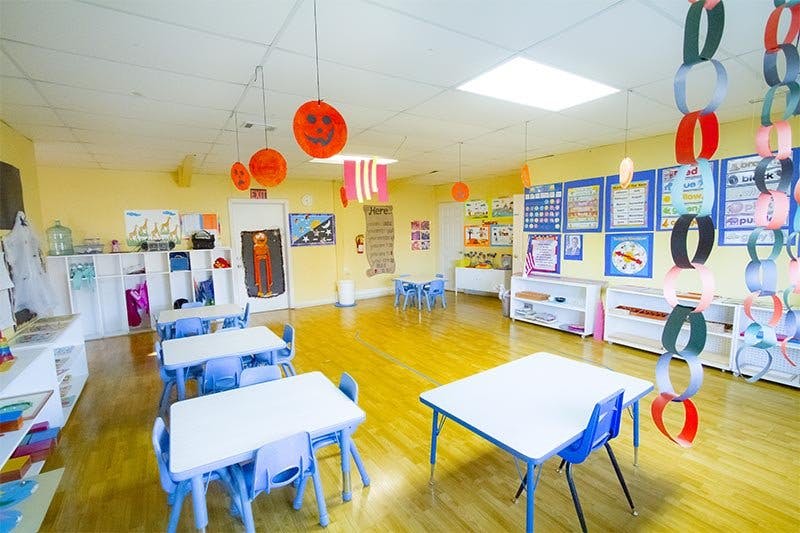 Empty classroom with small tables and chairs, decorated with paper chains and cutouts