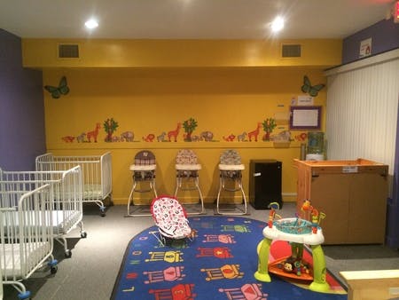 Nursery room with cribs, high chairs, and play mat