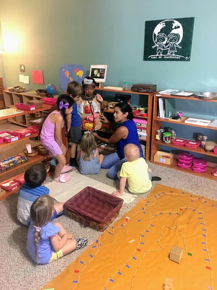 Adult and children gathered around a table in a classroom