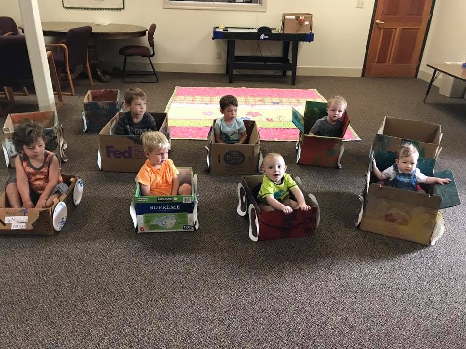 Children sitting in cardboard box cars