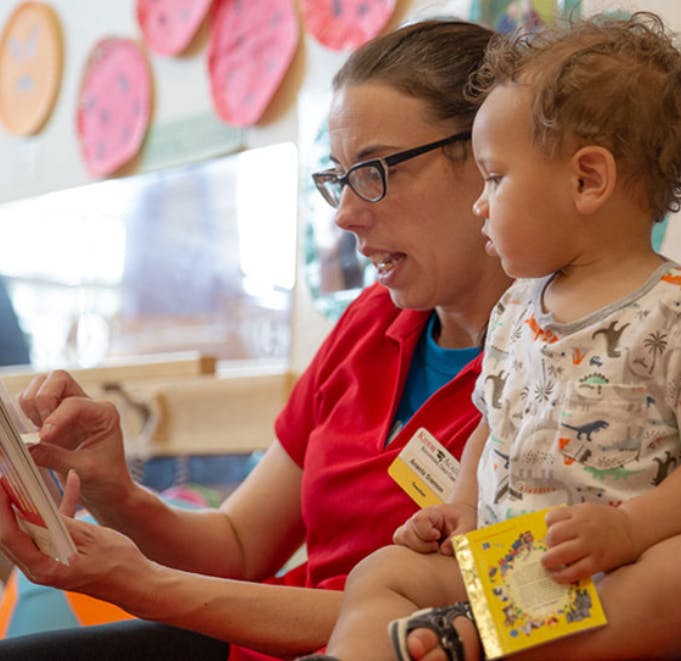 Person in glasses reading a book to a child