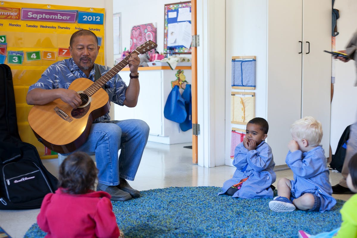 Person playing guitar for children in a classroom