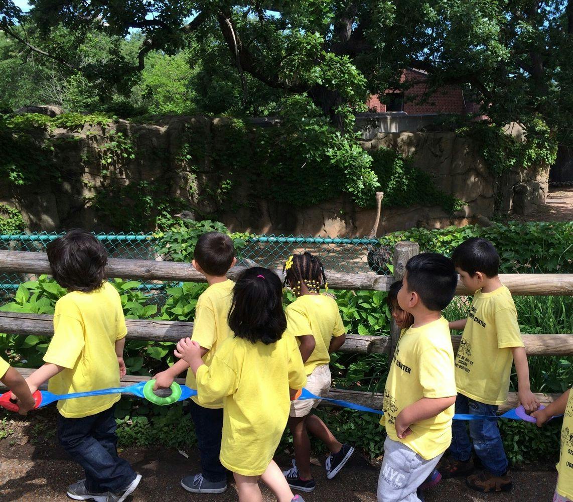 Children in yellow shirts holding a blue rope outdoors