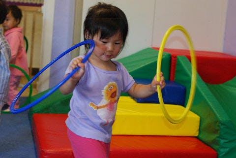 Child holding a blue hoop and a yellow hoop