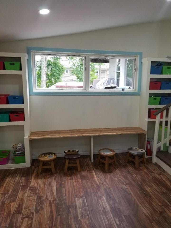 Room with window, built-in shelves, long wooden bench, and small stools