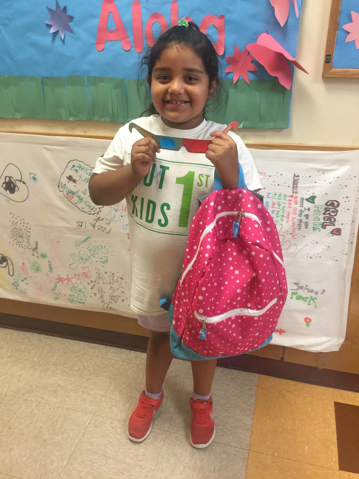 Child holding 3D glasses and a pink backpack