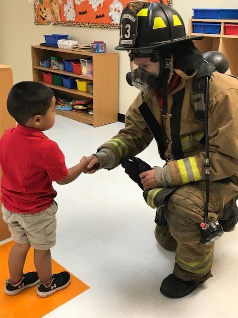 Firefighter in uniform shaking hands with a child