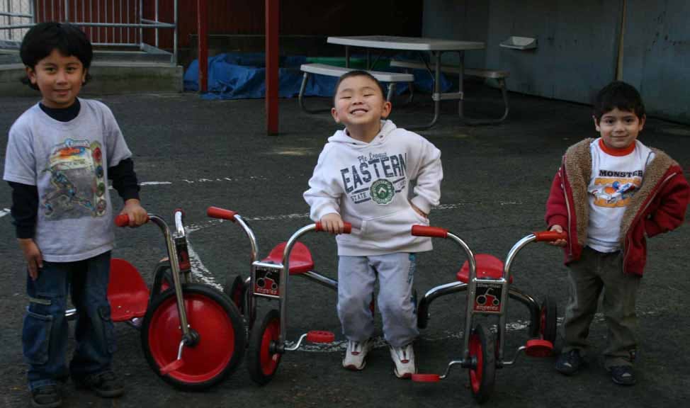 Three children standing with tricycles