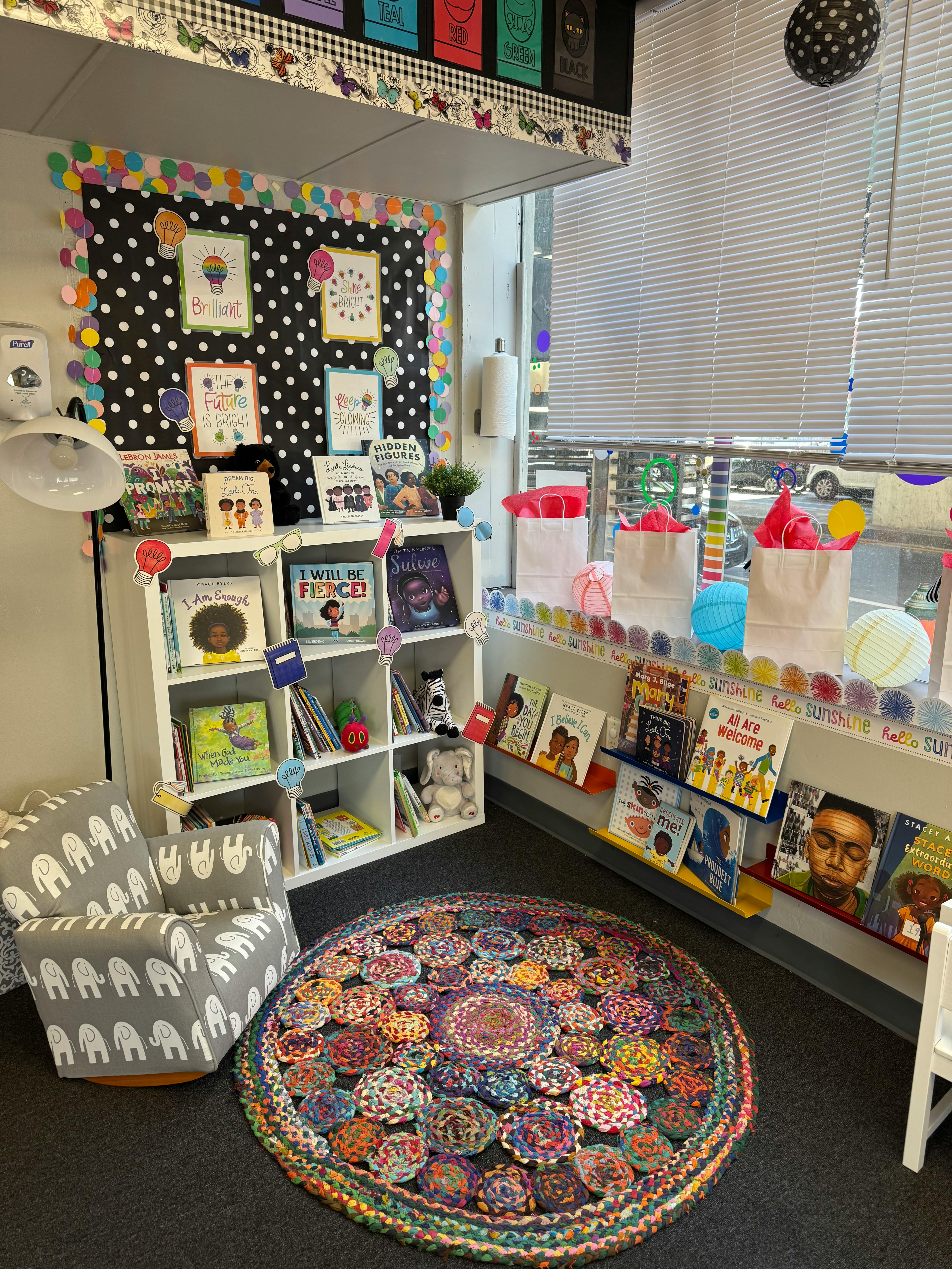 A classroom reading nook with bookshelves, a patterned rug, and a chair