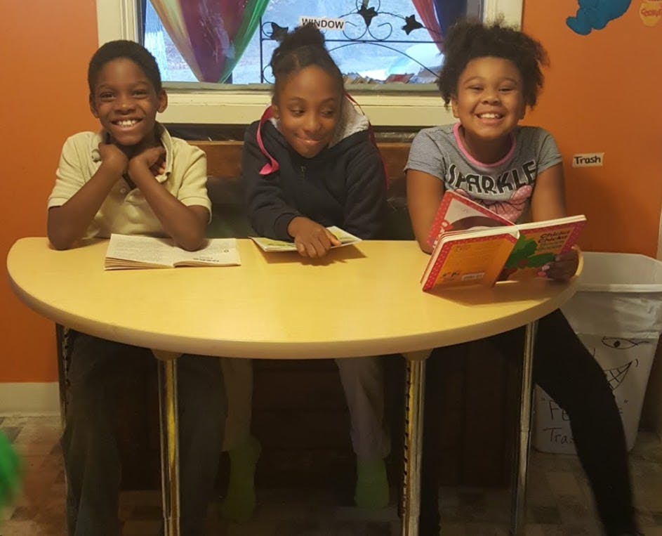 Three children sitting at a table with books