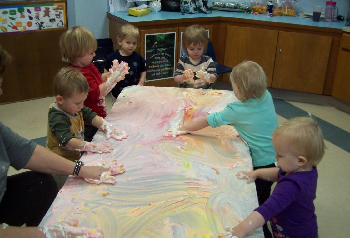 Children and an adult playing with paint on a table