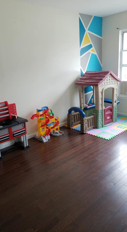 Playhouse and other toys in a room with a geometric accent wall