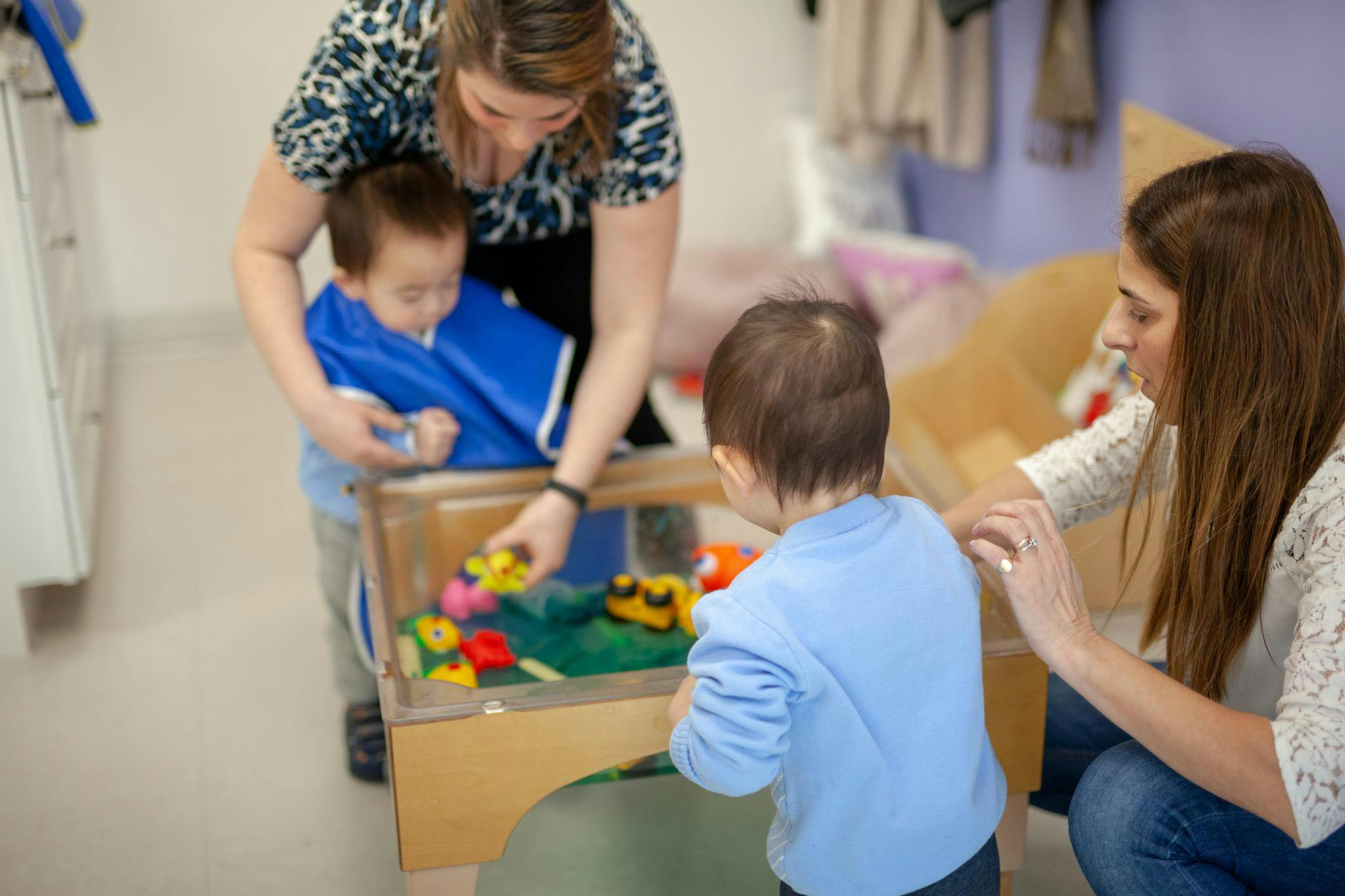 Two adults and two children playing with toys at a table