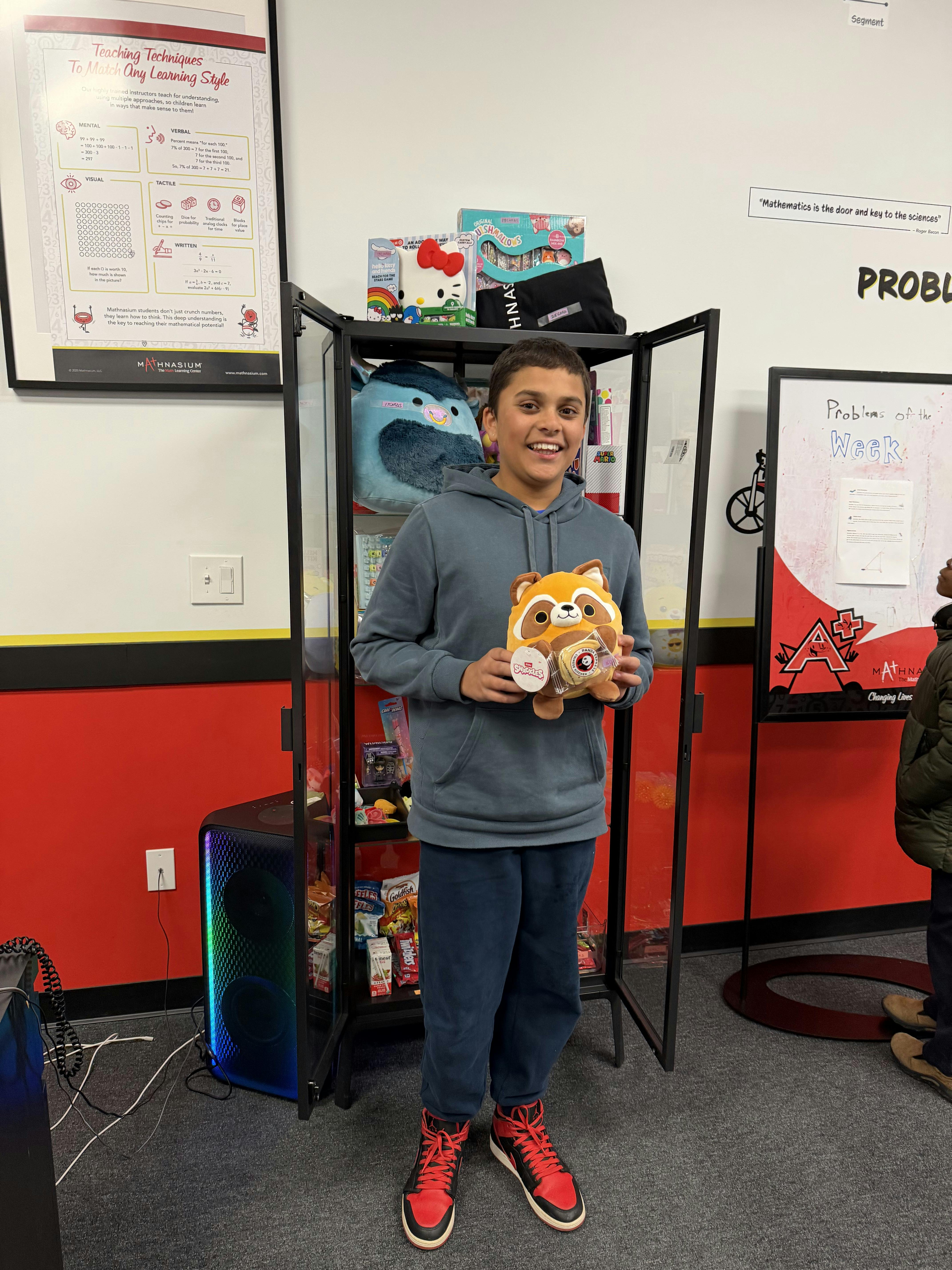 A child in a gray hoodie holding a brown and orange plush toy