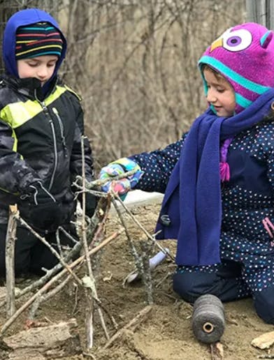 Two children building a structure with sticks