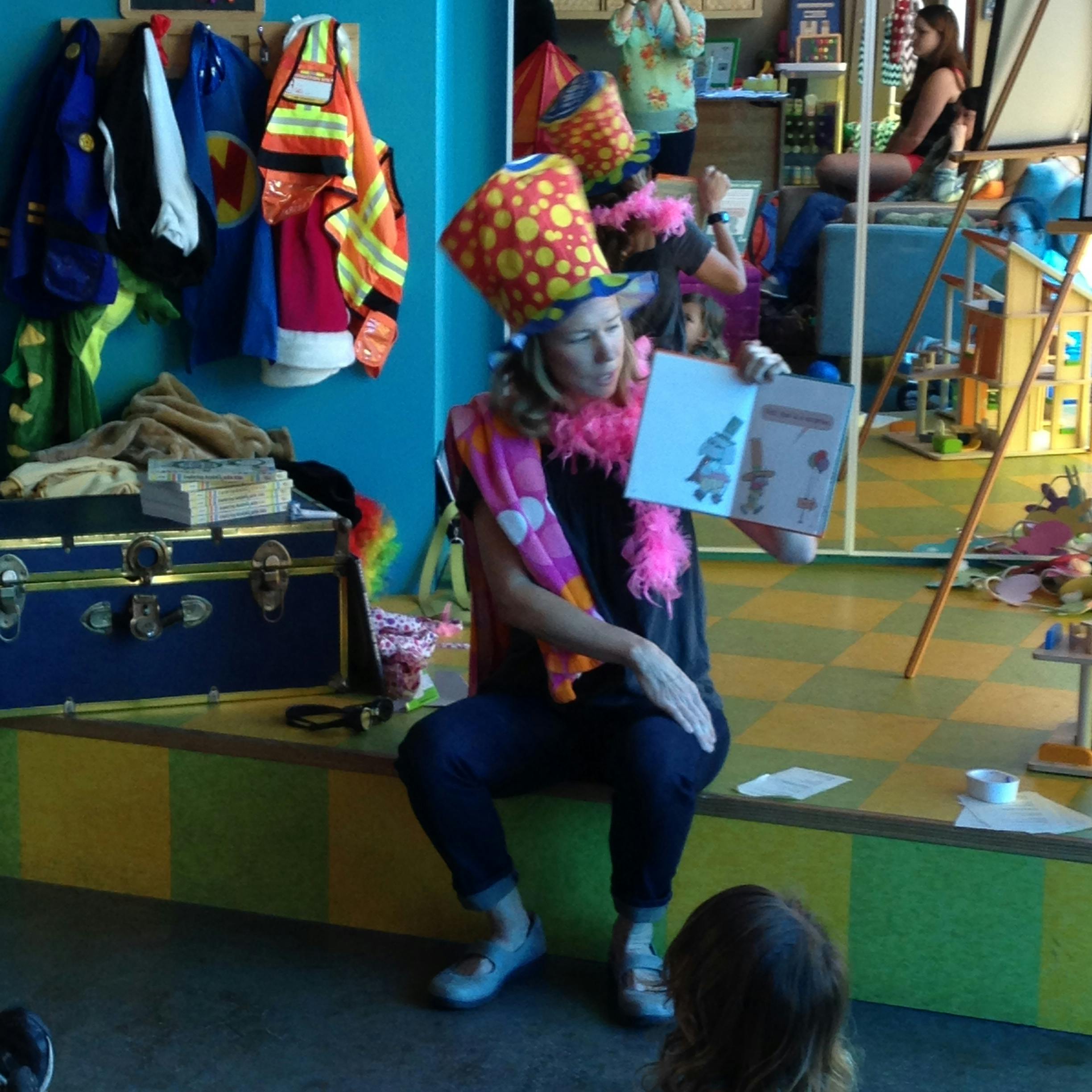 Person in a tall hat and boa reading a book to a child