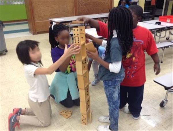 Children building a tall structure with dominoes