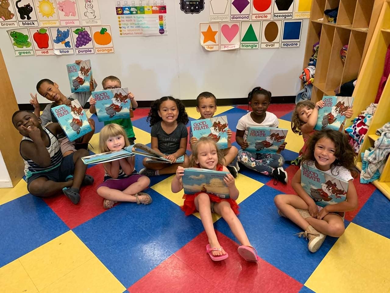 Group of children sitting on a colorful floor holding books
