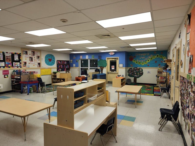 Empty classroom with small tables and chairs, and colorful decorations on the walls