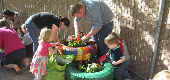 Adults and children planting in colorful tire planters