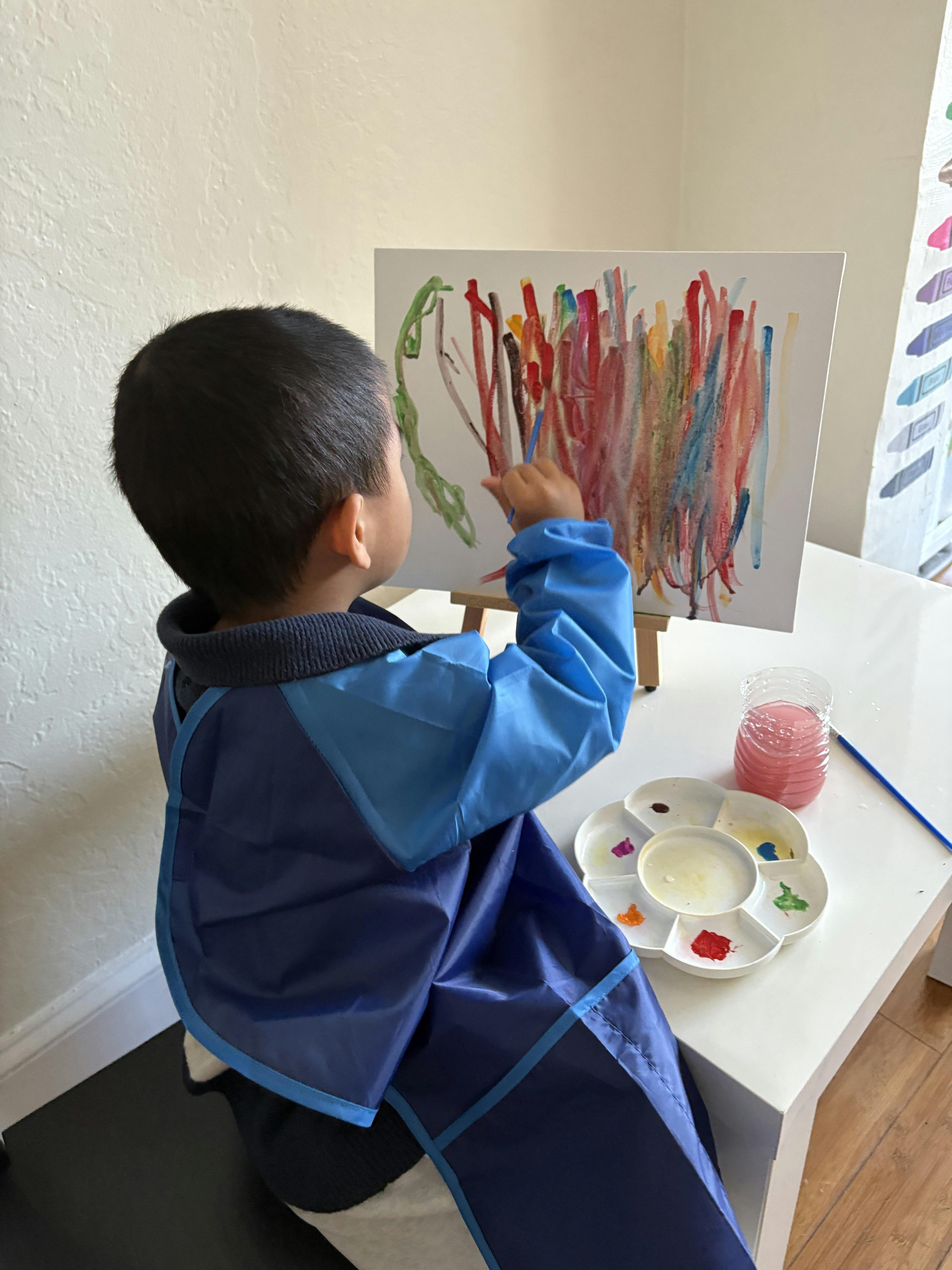 Child in smock painting on an easel