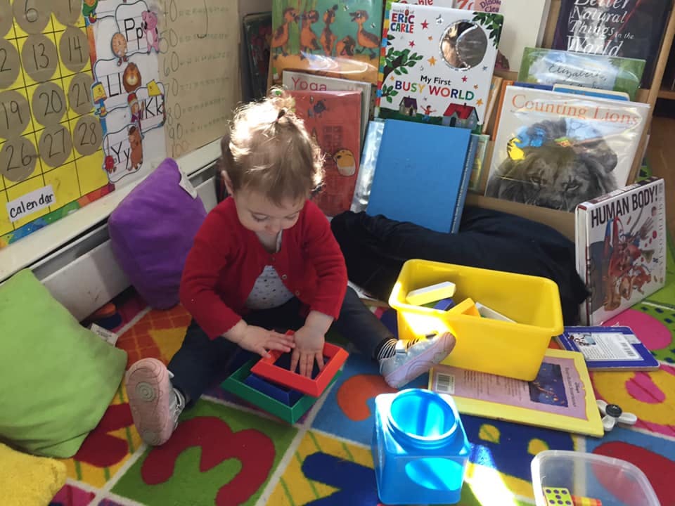 Child playing with colorful stacking toys on a patterned rug