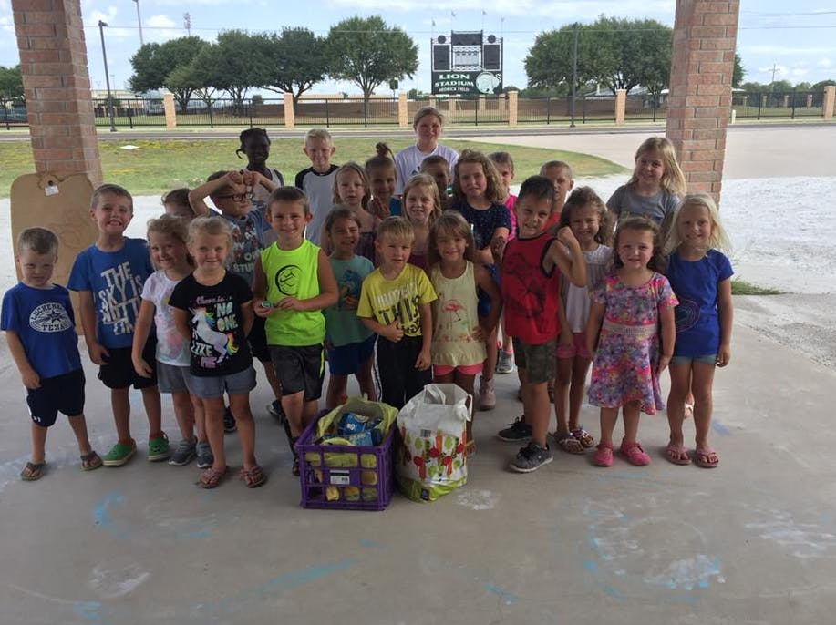 Group of children standing together outdoors with bags