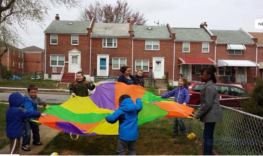 People and children playing with a colorful parachute