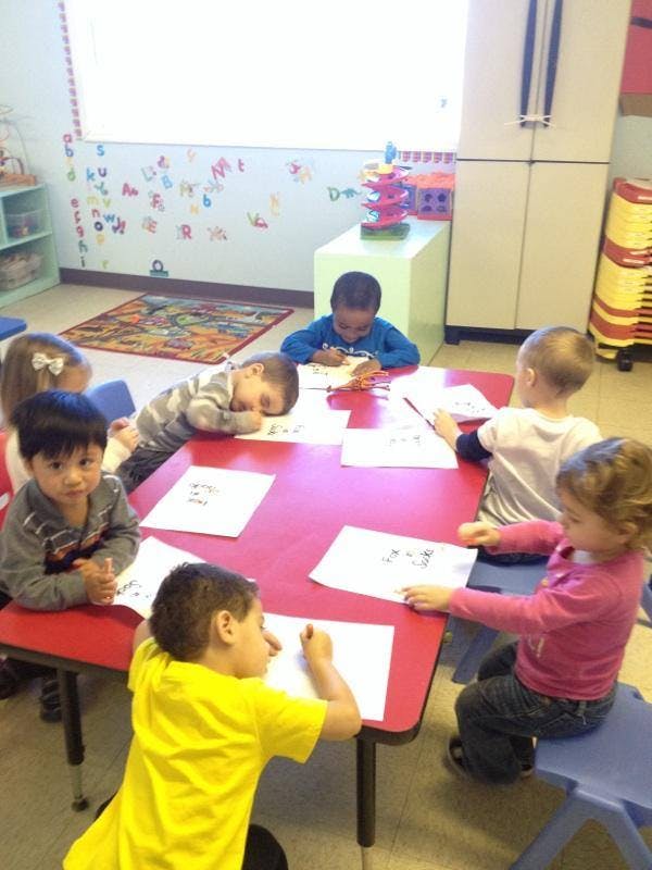 Children drawing at a red table in a classroom