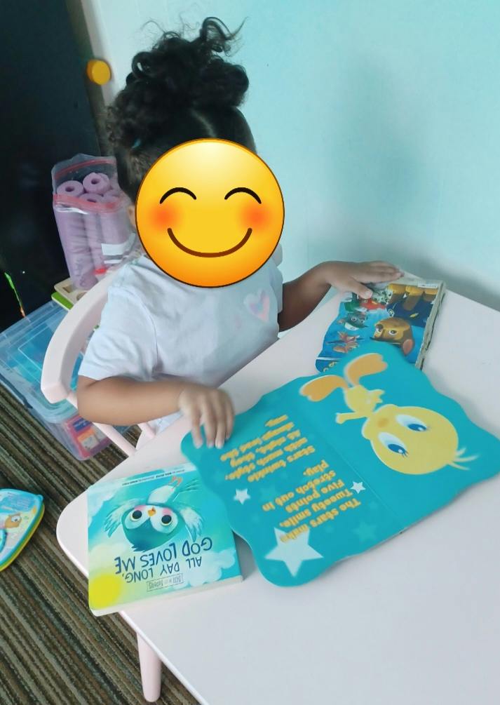 Child sitting at a small table reading board books